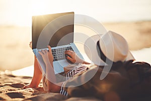 Young woman working with laptop on nature in beach
