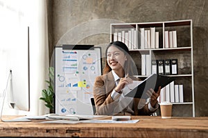 Young woman working on a laptop in the office. Asian businesswoman sitting at her workplace in the office. Beautiful