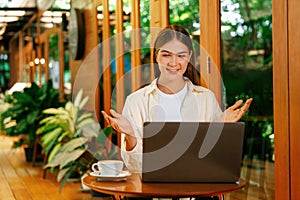 Young woman working on laptop at outdoor cafe garden. Expedient