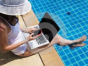 Young woman working on laptop at poolside