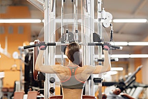 Young woman working at the lat pulldown machine in the gym,