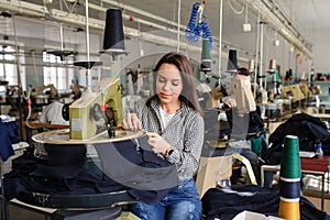 young woman working with linking machine for knitting in textile industry