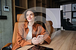 Young woman working in office, sitting with digital tablet, waiting for a meeting in conference room