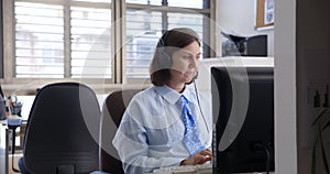 young woman working in the office and talking on a computer headset with colleagues