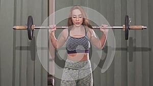 Young woman working out with a barbell with heavy weights on her shoulders