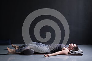 Woman working out, doing yoga exercise on wooden floor, lying in Shavasana photo