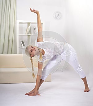 Young woman working out at home in living room. Teenager girl doing yoga or pilates exercise. Full length portrait