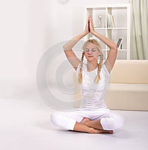 Young woman working out at home in living room. Teenager girl doing yoga or pilates exercise. Full length portrait