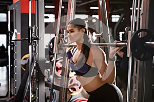 Young woman working out on Smith machine in gym