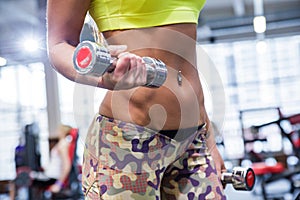 Young woman working out with two dumbbells