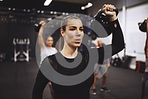 Young woman working out with weights in a gym class