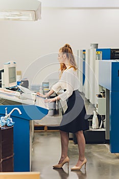 Young woman working in printing factory. Printing Press.