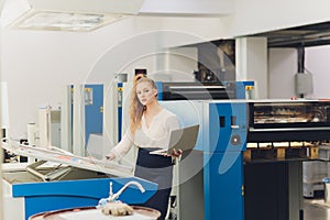 Young woman working in printing factory. Printing Press.