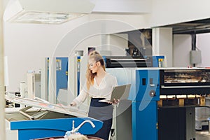 Young woman working in printing factory. Printing Press.