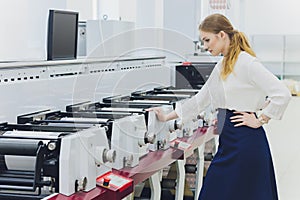 Young woman working in printing factory. Printing Press.