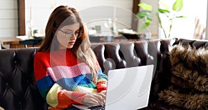 Young woman working remotely behind a laptop, home office