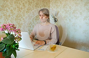 The young woman is working remotely at the computer without leaving home