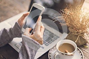 Young woman working by using cellphone and laptop