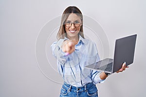 Young woman working using computer laptop pointing to you and the camera with fingers, smiling positive and cheerful