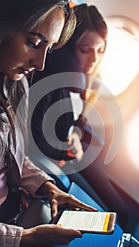 Young woman working, using a smartphone while flying in a plane.