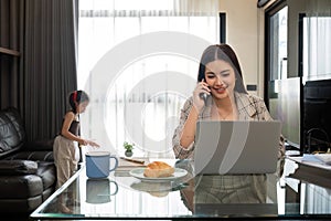 The young woman works from home, raises her daughter, and discusses work with co-workers on the phone and online.