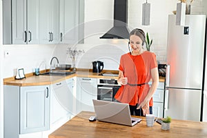 Young woman works from home using headset, laptop