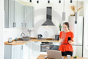 Young woman works from home using headset, laptop