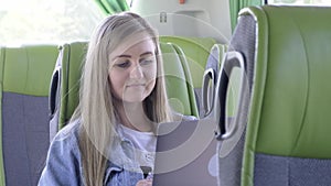 A young woman works on a laptop while traveling in public transport