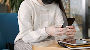 Young woman works in the office at the table. Woman user holding modern cell phone, business woman customer using social
