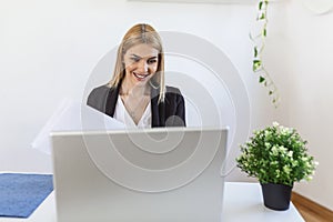 A young woman works remotely on a laptop in her apartment. A lady during a video business briefing at home. A pretty female