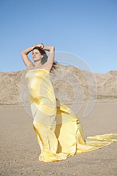 Young woman wrapped in yellow cloth on arid landscape