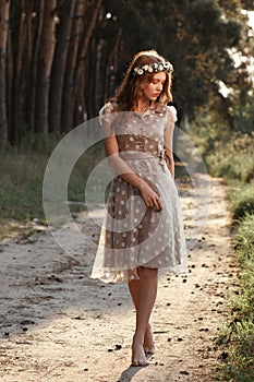 Young woman in wreath walking in forest barefoot