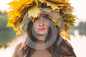 Young woman with a wreath of yellow autumn leaves. Outdoors portrait.