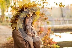 Young woman with a wreath of yellow autumn leaves. Outdoors portrait.