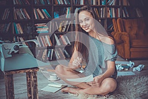 Young woman writer in library at home creative occupation looking camera smiling