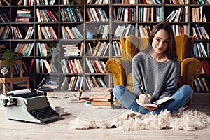 Young woman writer in library at home creative occupation sitting taking notes