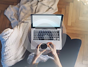 Young woman writes a text message on laptop keyboard with a empty blank screen monitor while having recreation time at home