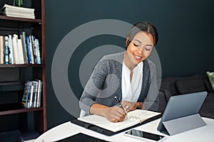 Young woman writing notes while working from home