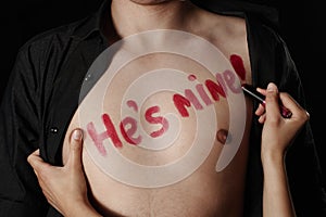 A young woman writing with a red lipstick phrase He is mine photo