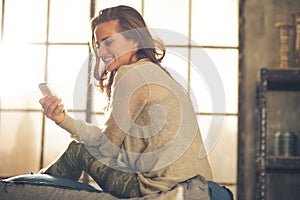 Young woman writing sms in loft apartment