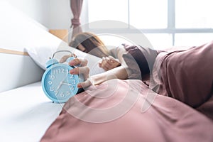 Young woman yawn awakening tired holding alarm clock. wake up early in morning. Girl stop snooze alarm. female waking up sleepy