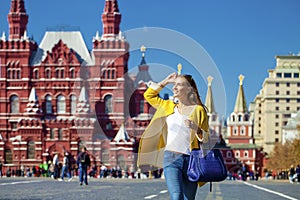 Young woman in yellow coat walks on the Red Square in Moscow