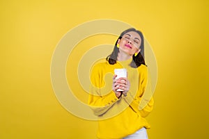 Young woman in a yellow cozy sweater with bright pink lip gloss with a paper cup