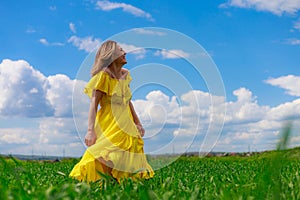 Young woman in yellow dress outdoors in green field. The concept of love of life and openness to the world