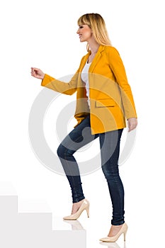 Young Woman In Yellow Jacket And High Heels Is Walking Up The Stairs. Side View