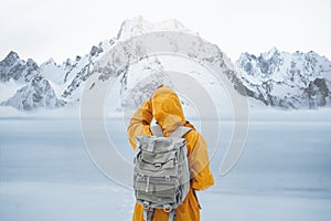 Young woman in yellow jacket travel while her holidays and looking away winter mountain