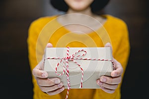 Young woman in yellow sweater holding gift box for spacial event