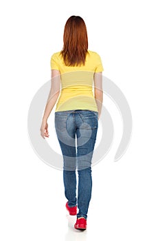 Young Woman In Yellow T-Shirt, Jeans And Red Sneakers Is Walking. Rear View.