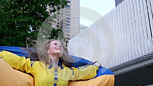 a young woman in a yellow vyshyvanka with the flag of Ukraine jumps rejoices at the Victory flag develops. Blue