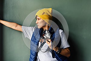 Young woman in yellow warm hat looking onside and holding photo camera . Portrait. Technology